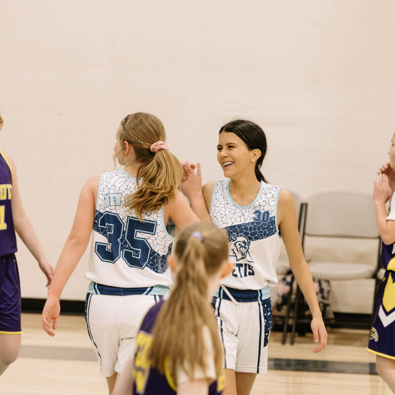 two players high five during middle school basketball game